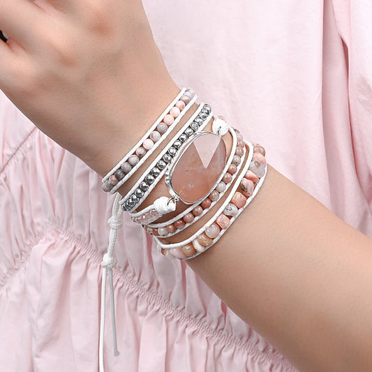Modelo usando a Pulseira de pedras naturais Ayla com Opala Rosa, Quartzo Rosa, Jaspe Rosa e Hematita no pulso, destacando seu design artesanal em delicados tons rosados.