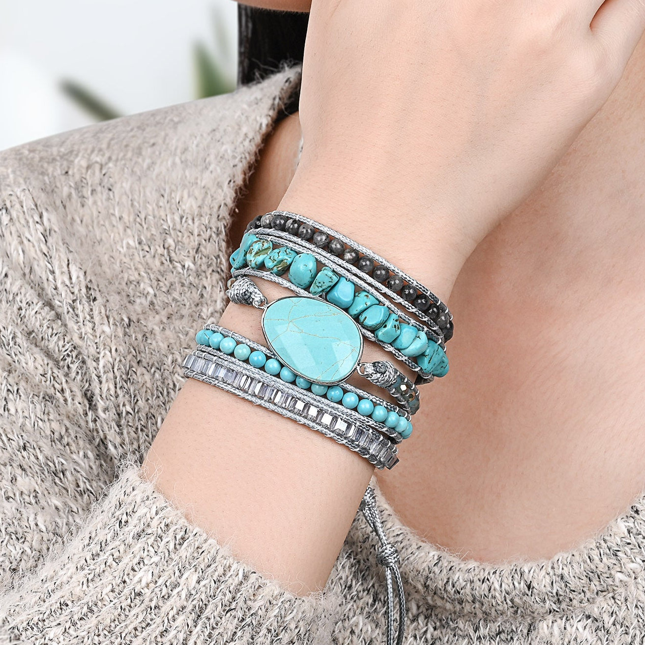 Modelo usando a Pulseira de pedras naturais Brisa com Turquesa e Labradorita no pulso, destacando seu design artesanal em tons de azul.