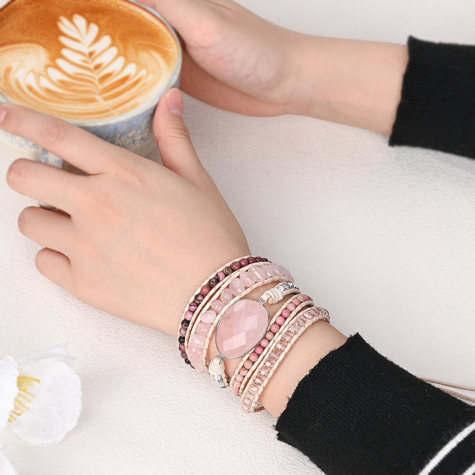 Modelo usando a Pulseira de pedras naturais Rose com Quartzo Rosa e Rodonita no pulso, destacando seu design artesanal e elegante.