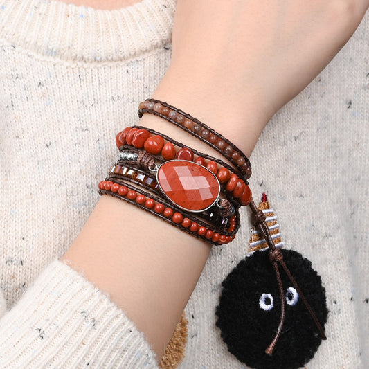Modelo usando a Pulseira de pedras naturais Siena com Jaspe Vermelho, Quartzo Vermelho e Hematita no pulso, destacando seu design artesanal em tons avermelhados.