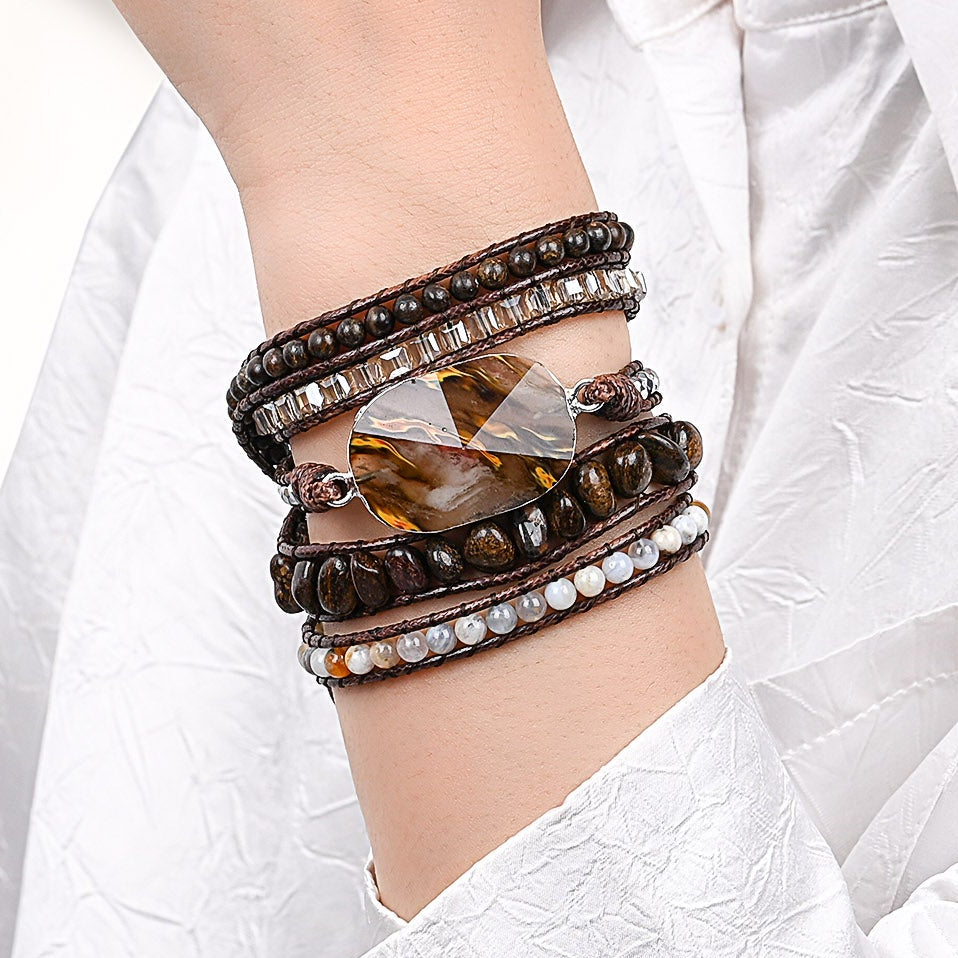 Modelo usando a Pulseira de pedras naturais Verona com Bronzita, Calcedônia, Ágata Botswana e Hematita no pulso, destacando seu design artesanal em tons terrosos.
