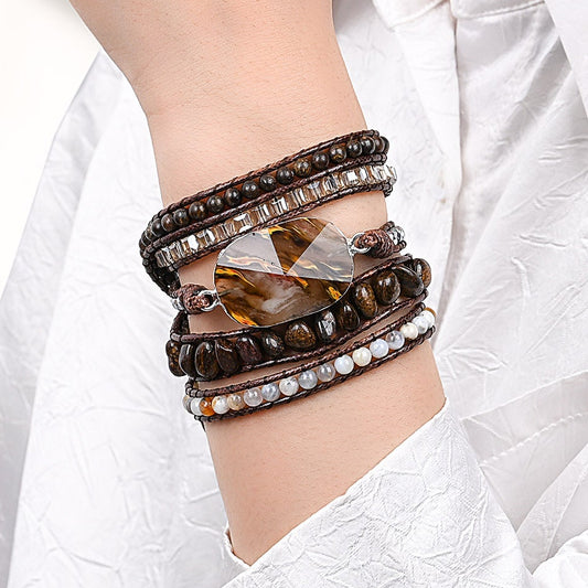 Modelo usando a Pulseira de pedras naturais Verona com Bronzita, Calcedônia, Ágata Botswana e Hematita no pulso, destacando seu design artesanal em tons terrosos.