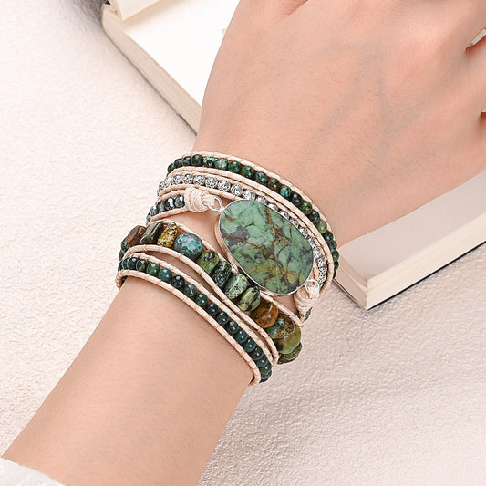 Modelo usando a Pulseira de pedras naturais Zuri com Turquesa Africana e Ágata Indiana no pulso, destacando seu design artesanal em tons naturais de verde.